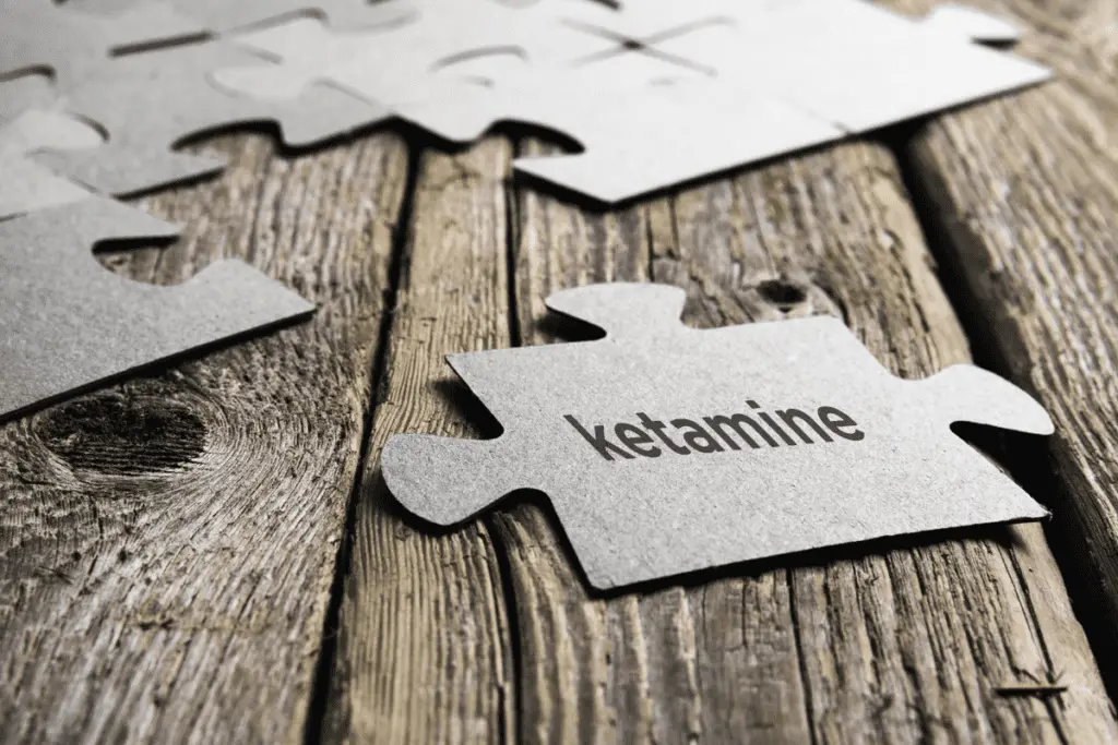Puzzle piece with 'ketamine' text on wooden surface for mental health treatment.