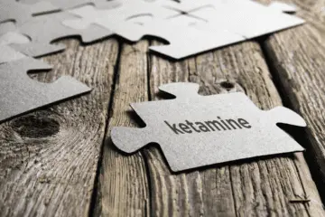 Puzzle piece with 'ketamine' text on wooden surface for mental health treatment.