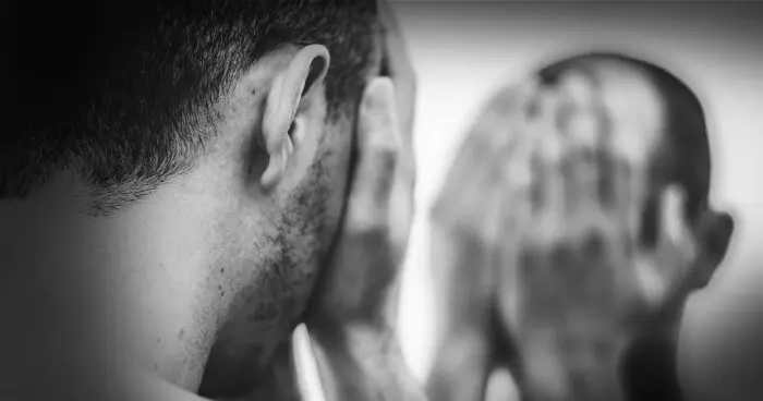 Person in distress holding their head, reflecting emotional pain and mental health struggles.