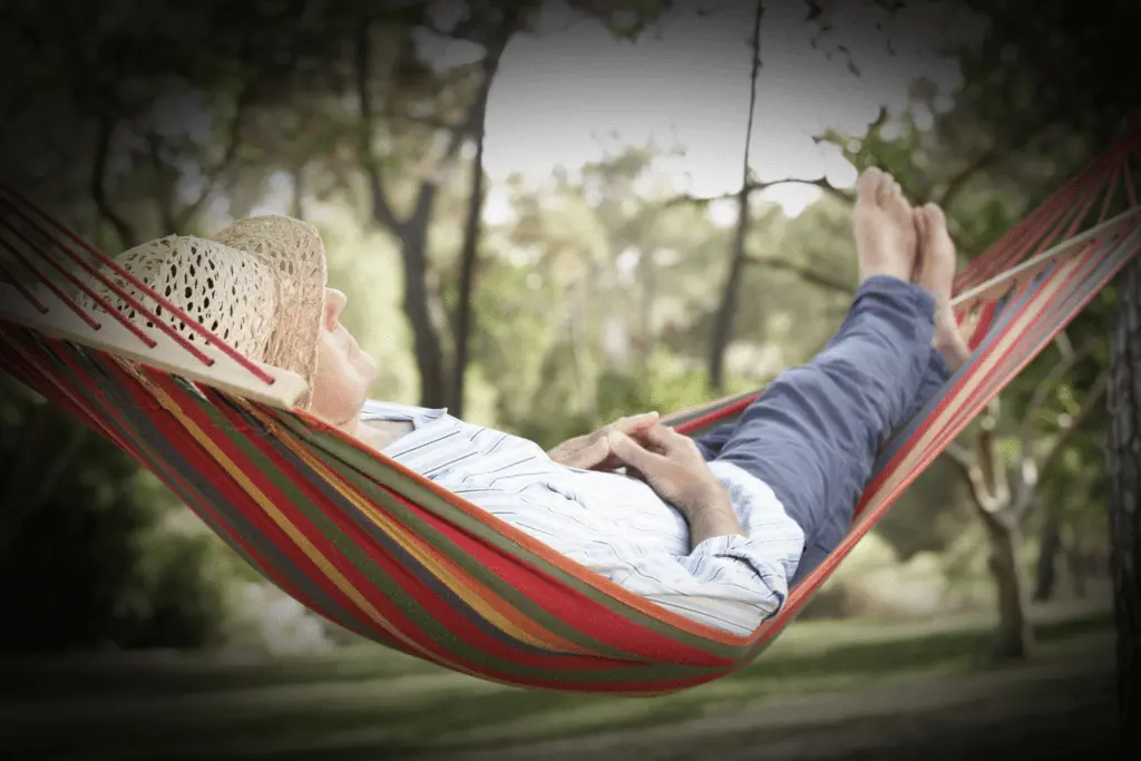 Person relaxing in a hammock outdoors for mental health and relaxation.