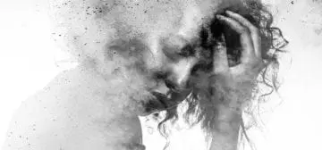 Woman with curly hair holding her head in distress, symbolizing depression.