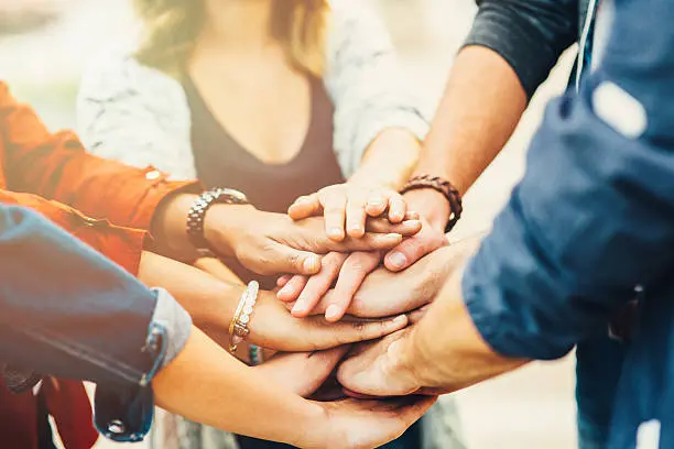 Group of diverse people stacking hands in teamwork and unity.