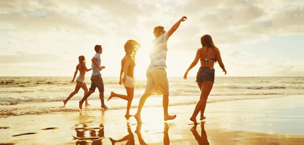 Happy family playing on the beach at sunset with ocean waves.