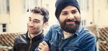 Two men smiling outdoors, representing mental health support and community.