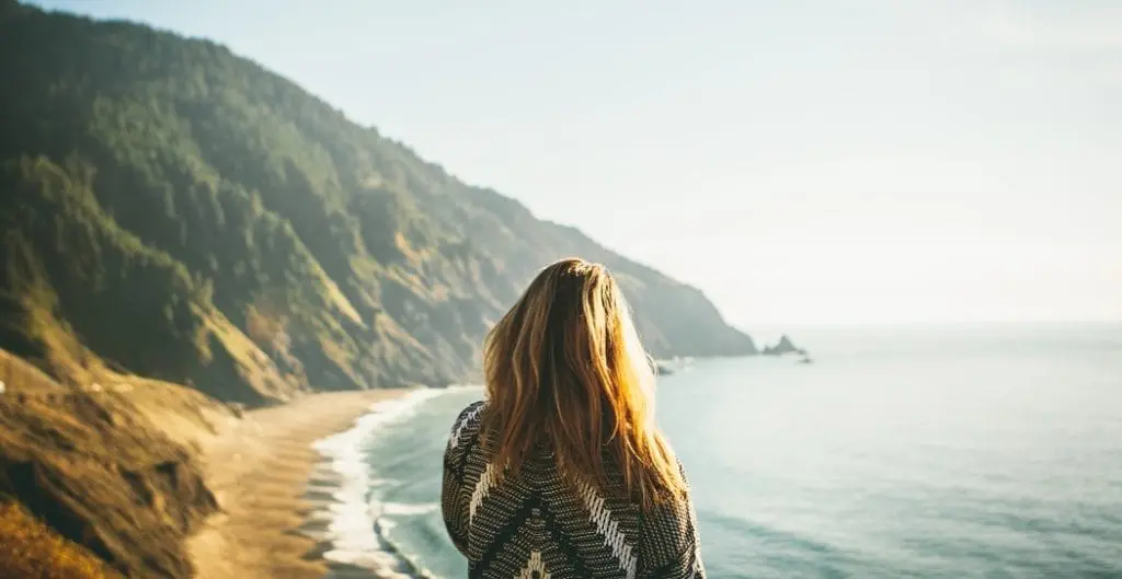 woman in sweater overlooking a bluff over the ocean