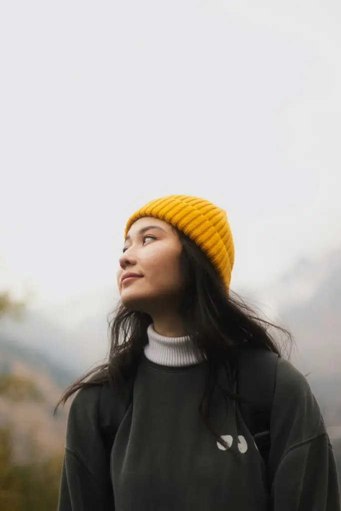 Young woman with a yellow beanie enjoying nature for mental wellness.
