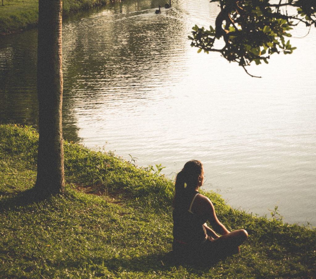 Woman sitting cross-legged next to a lake