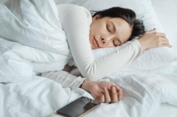 Woman sleeping on bed with her phone next to her
