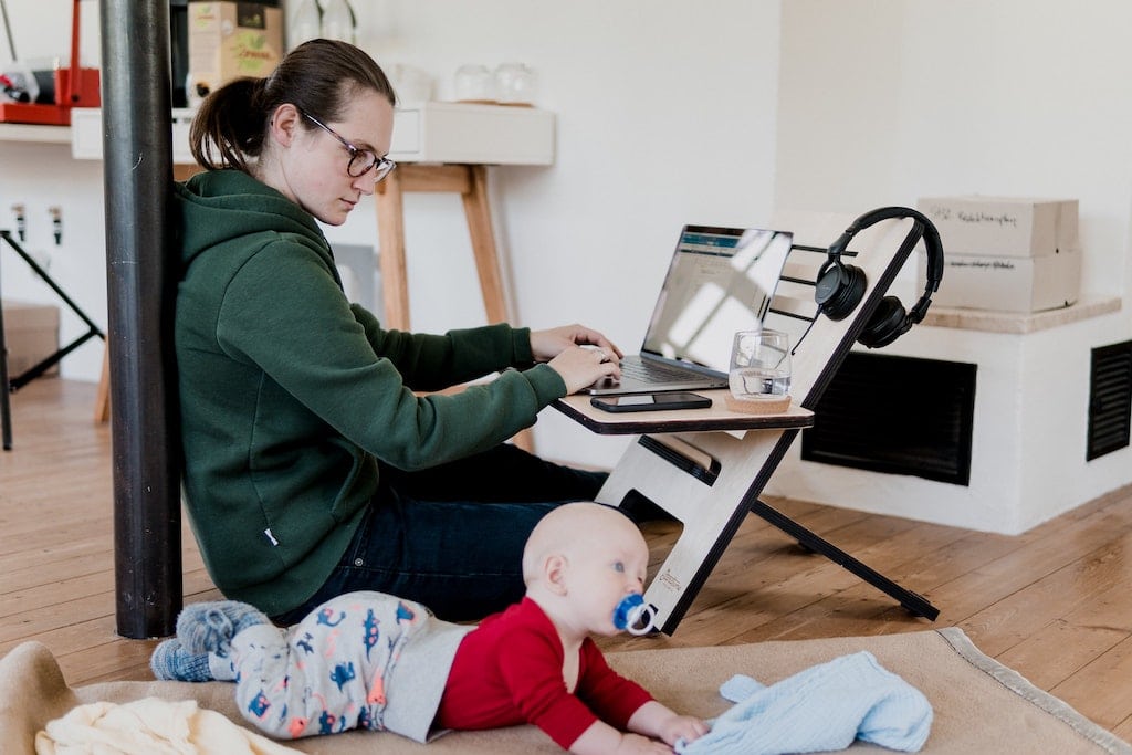 woman working at home with young toddler