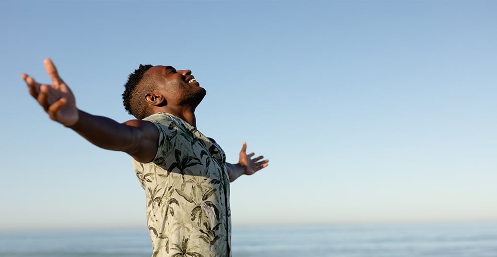 happy man walking on the beach with arms outstretched