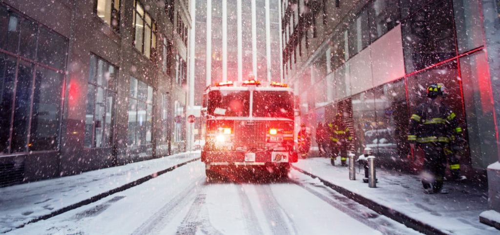 Firetruck with lights on going down snowy city street