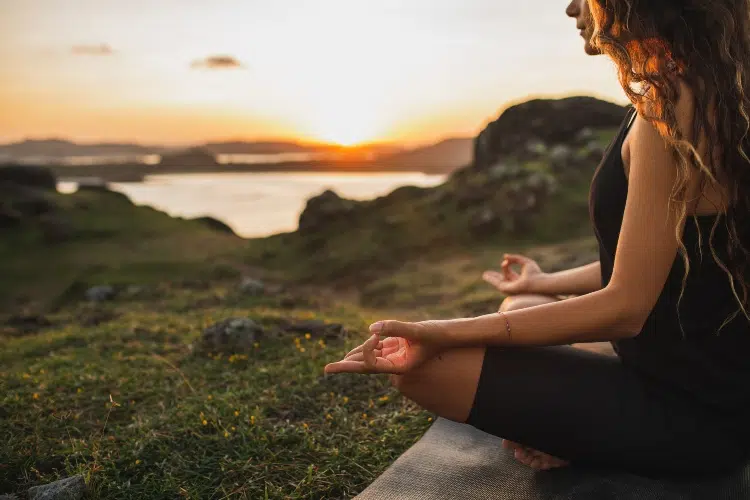 A woman meditating by the ocean for topic Partial Hospitalization Program.