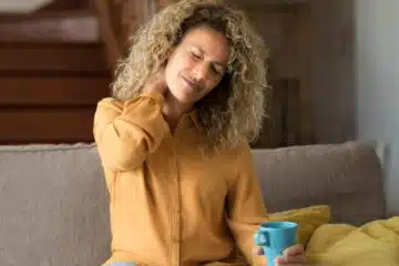 Tired young woman touch stiff neck feeling hurt joint back pain rubbing massaging tensed muscles