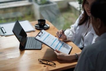 Female health insurance broker presenting his insurance benefits to man fill out insurance policy.