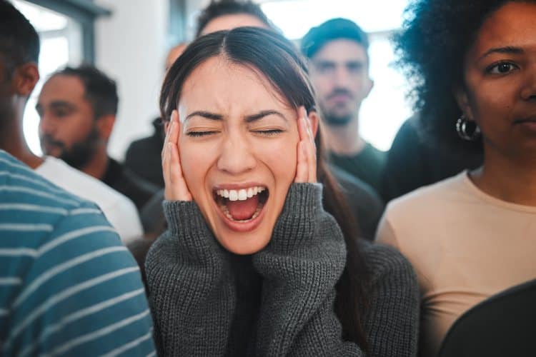 young woman experiencing panic while being surrounded by people