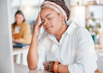 woman exhausted and overwhelmed with workload in office.