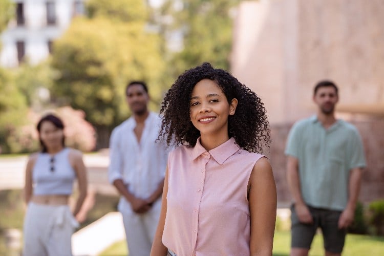 Young black woman is smiling in the foreground with three friends standing behind her out of focus