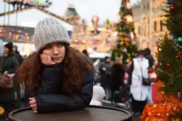 Young woman with a gray knit hat at a festive holiday market.