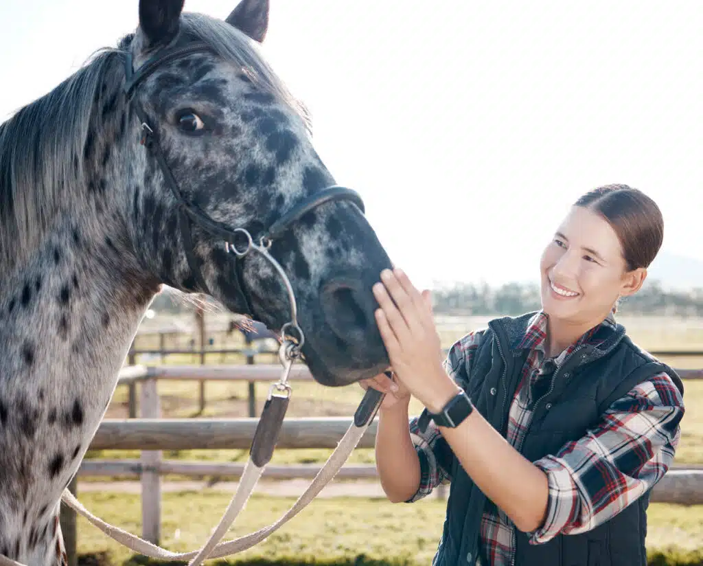 A woman smiling next to a horse for the topic does insurance cover equine therapy.