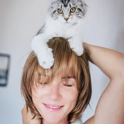 happy woman with a cat on her head