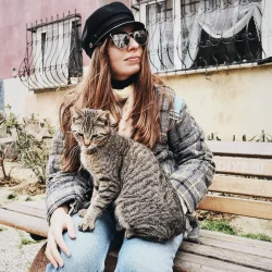 woman sitting on a bench outdoor with a cat